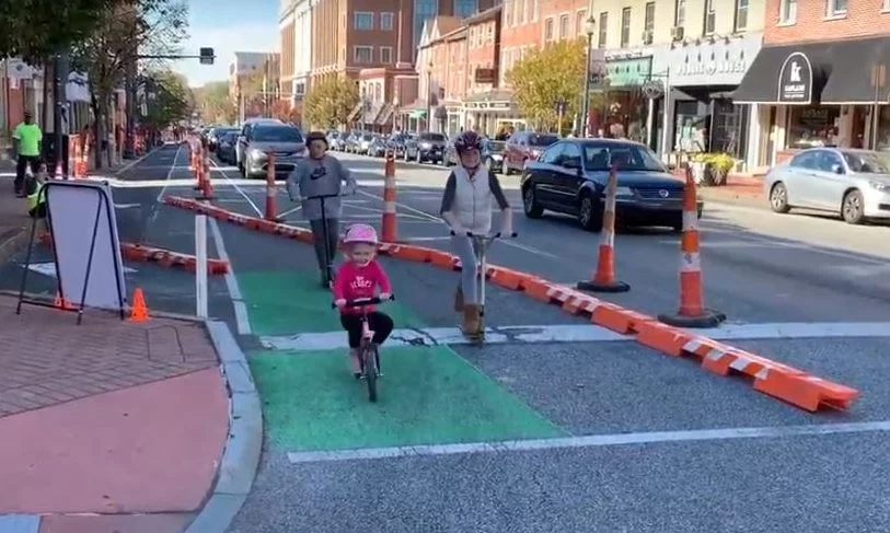 Children and adult biking along the temporary protected bike lane during day of demonstration.