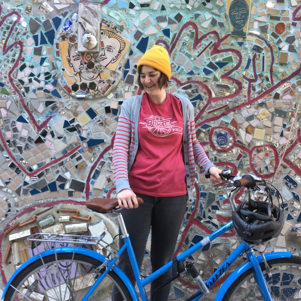 Former Marketing and Development Manager Ashley Vogel with her bike in front of a mosaic in South Philly