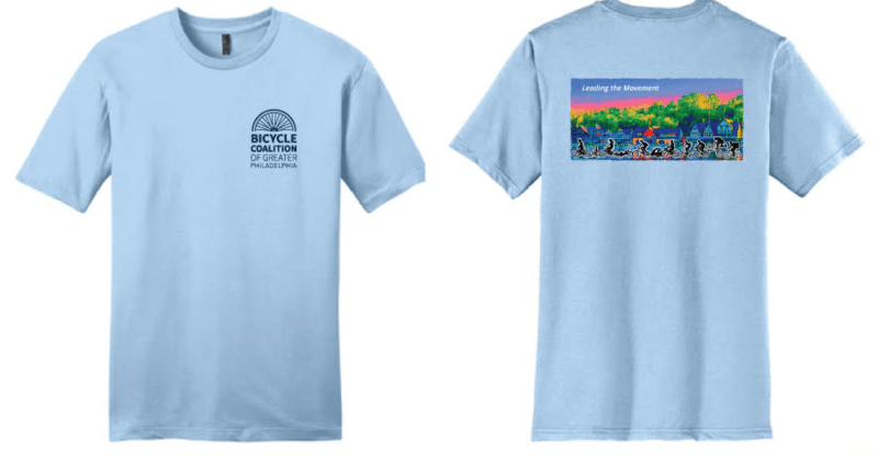 Front and back of the Bicycle Coalition 2021 tshirt. Front (l): light blue with Bicycle Coalition logo on pocket. Back (R): boathouse row in technicolor in the background, variety of cyclists on all different types of bikes in the foreground.