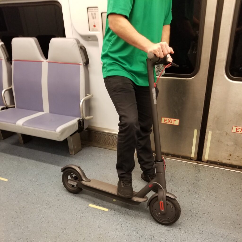 A passenger holding their e-scooter on the PATCO High Speed Line.